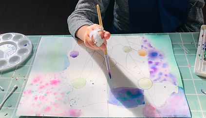 a photograph of a child painting a watercolour painting.