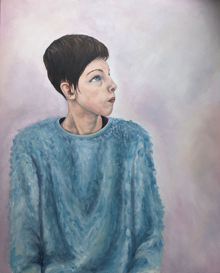 Portrait of a young girl looking to her right and up. She is wearing a blue jumper.