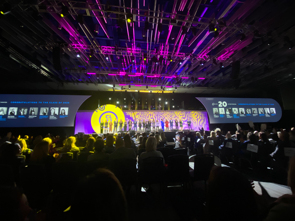 High production general session stage with lighting, screens, and full audience at corporate conference