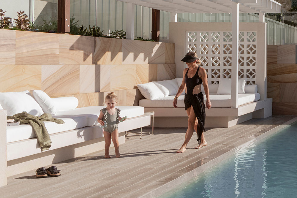 Fully tiled perimeter edge spill over concrete pool with custom built cabana and daybed, Millwood decking and sandstone retaining on the Central Coast | Design and build by Luxury Pools & Outdoor Living