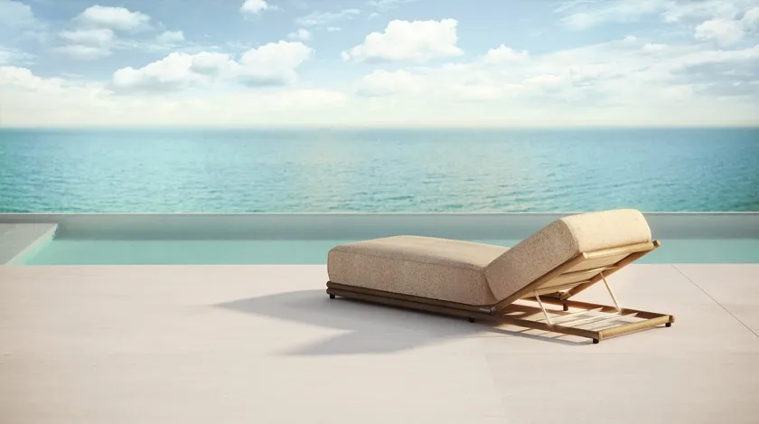 Posh gold and plush cushioning sun lounger chair looking out over the ocean