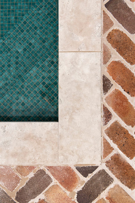 Detail of the corner of the green mosaic pool tiles contrasting the herringbone brick decking.
