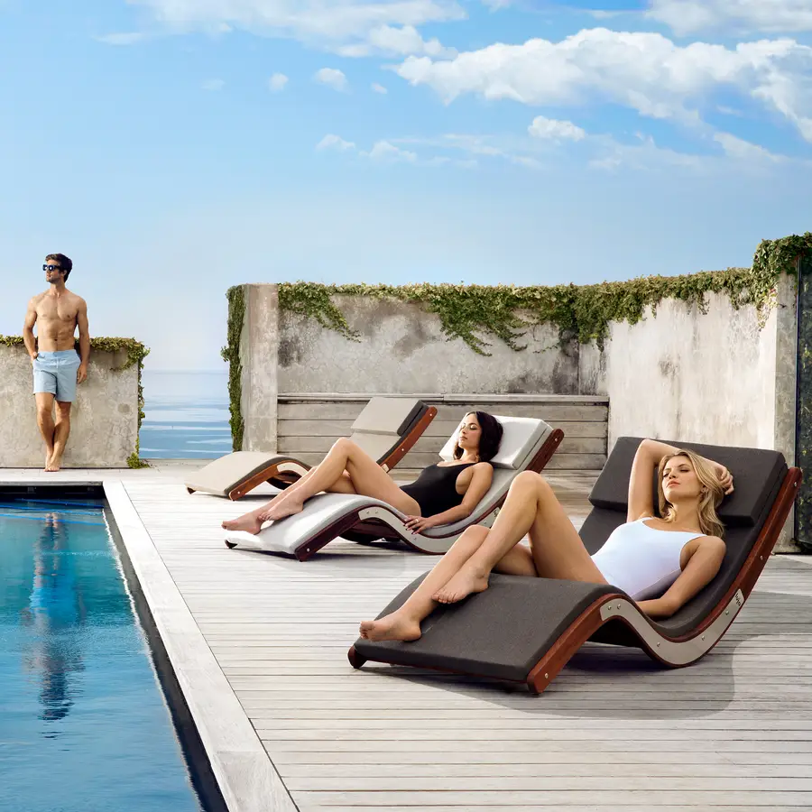 Women enjoying the elegant design of the curved sun loungers and head cushion. The curve is a nice contrast to the sharp corners of the pool and landscape design