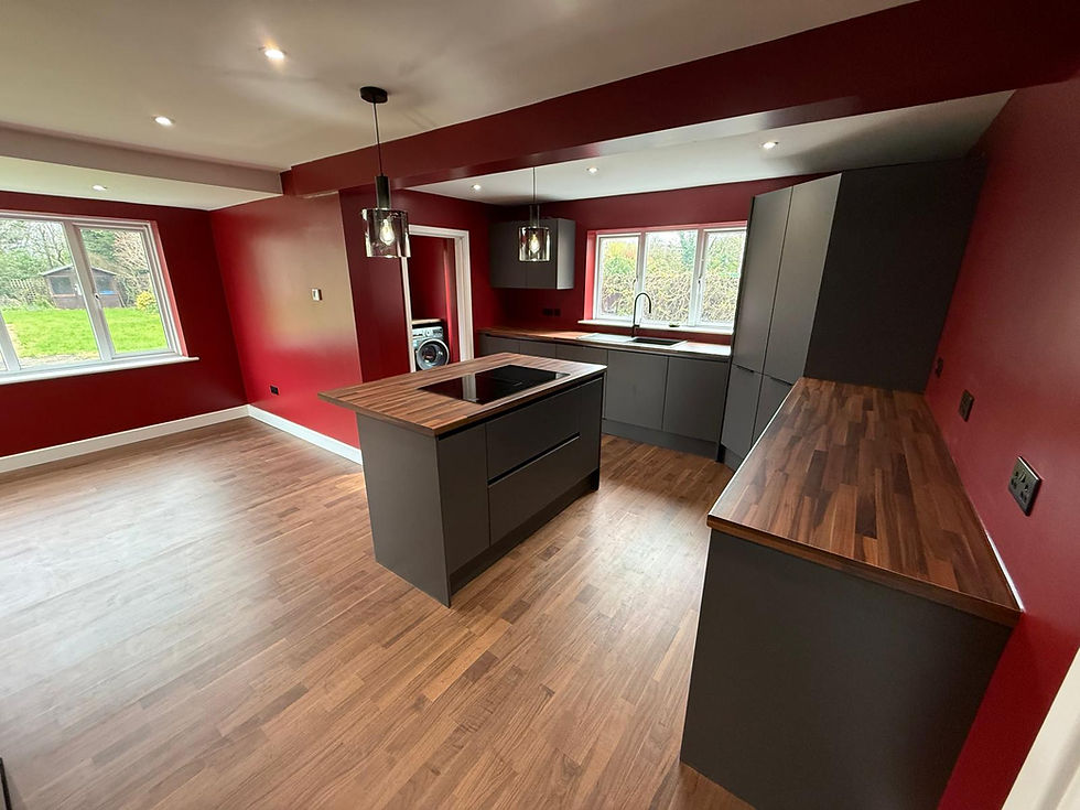 Grey handleless kitchen with walnut worktops and an island against red walls