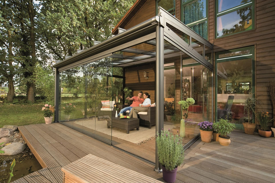 Weinor glass room with sliding glass sides attached to a timber-clad home