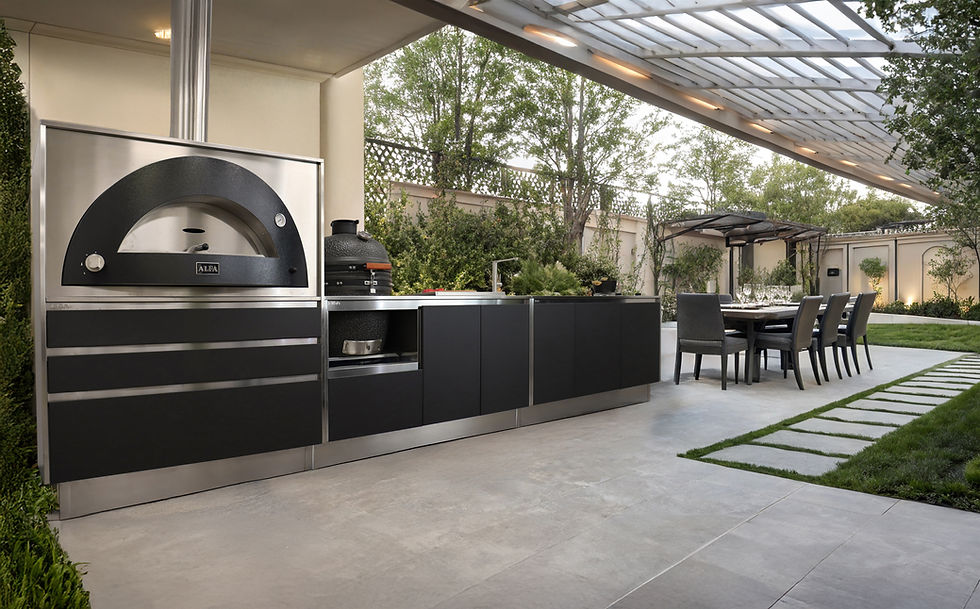 Black and stainless outdoor kitchen with a domed pizza oven running along a wall under a glass roof