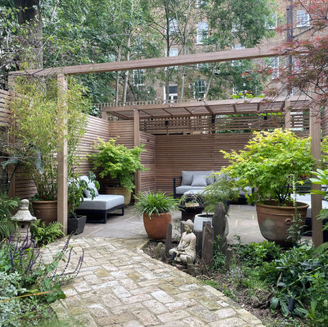 Lush London garden with cedar screening, potted plants and layered textures.
