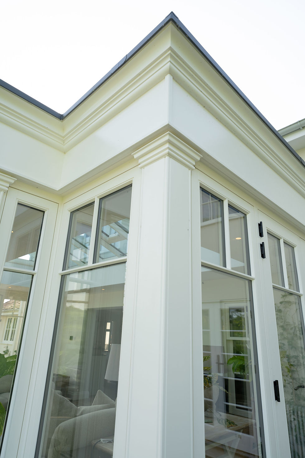 White painted timber orangery corner pilaster with moulded capital and deep entablature above tall glazing