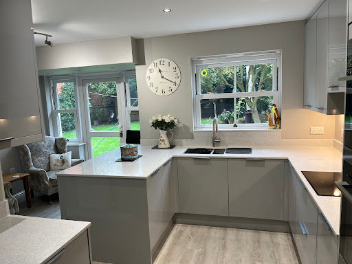 Light grey U-shaped kitchen with quartz worktops and a garden view