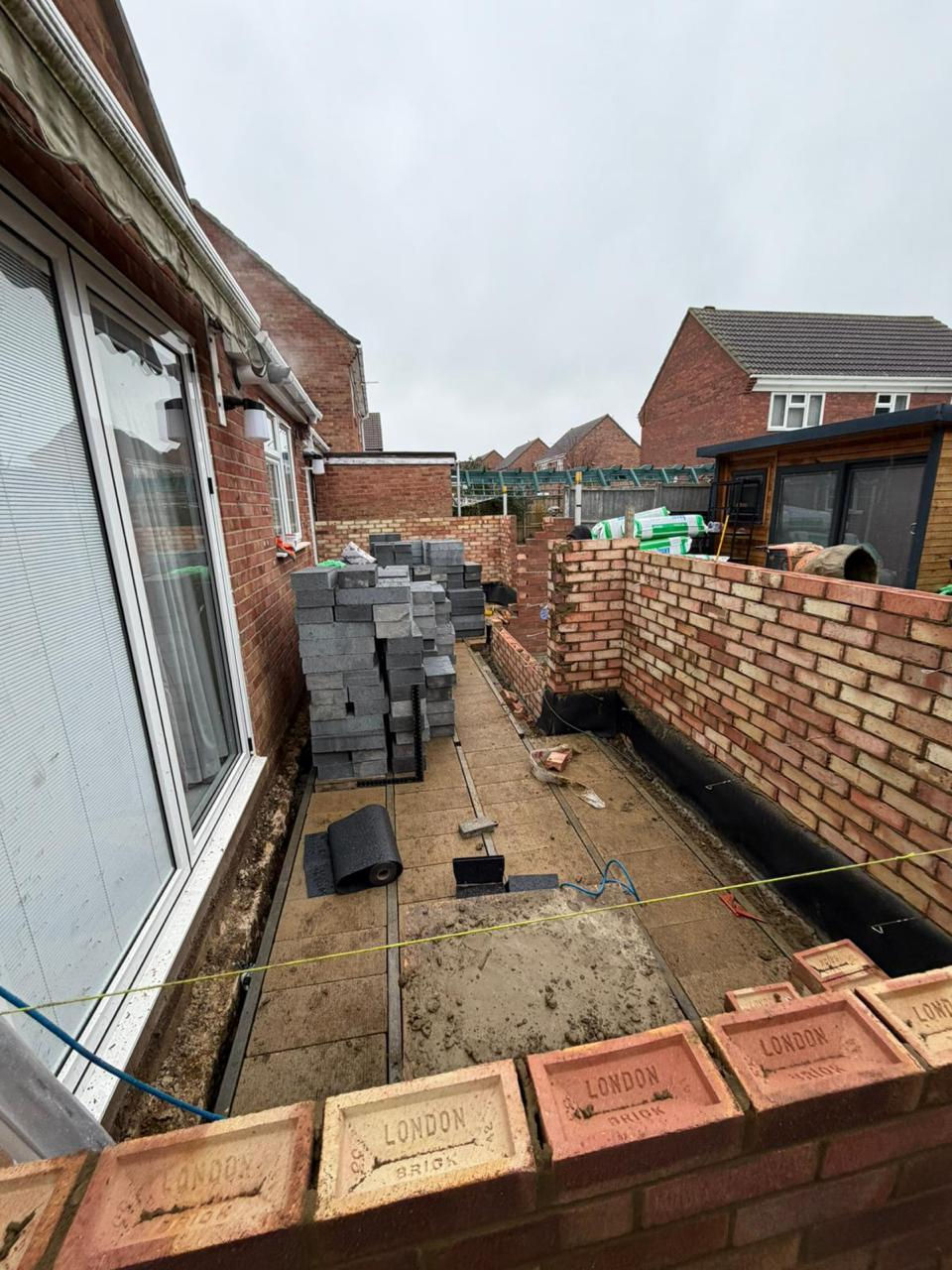 Single-storey extension walls rising with blocks stacked on site