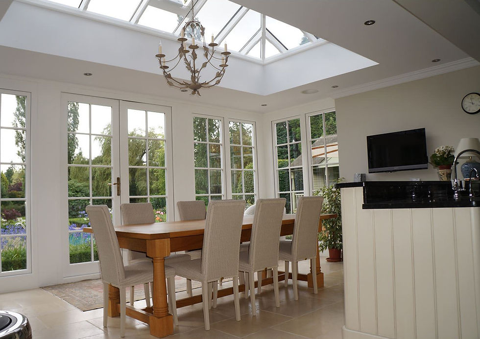 Orangery kitchen-diner with oak table, chandelier and white roof lantern, French doors to the garden