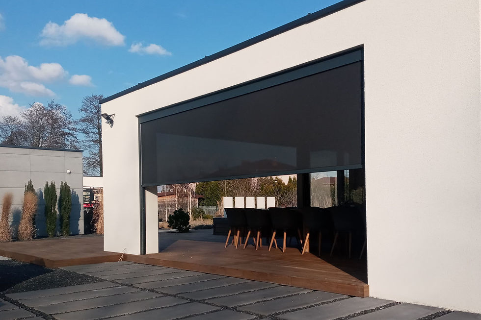Dark external zip screen lowered across the wide opening of a covered terrace on a white modern house