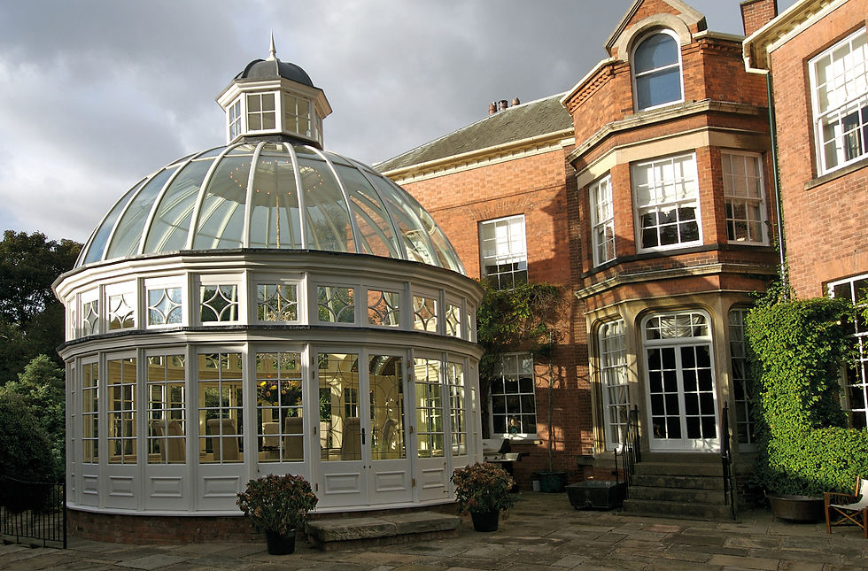 White painted timber dome conservatory with a glazed roof and cupola beside a red-brick Georgian house