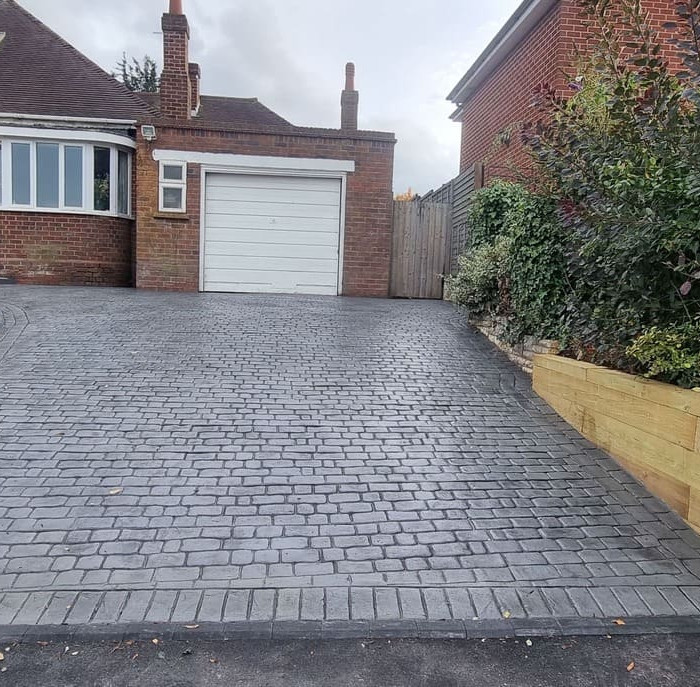 Charcoal pattern imprinted concrete driveway with raised timber border.
