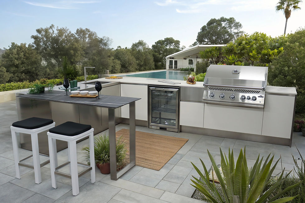Grey and stainless outdoor kitchen with a gas grill, drinks fridge and a bar counter with stools