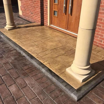 Brown pattern imprinted concrete patio by house entrance.