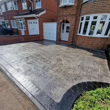 Pattern imprinted concrete driveway with curved border and brick edge.
