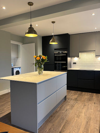 Grey kitchen island with space to walk around it and pendant lights above