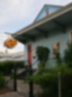 Historic New Orleans double shotgun house painted blue with neon sugar park sign
