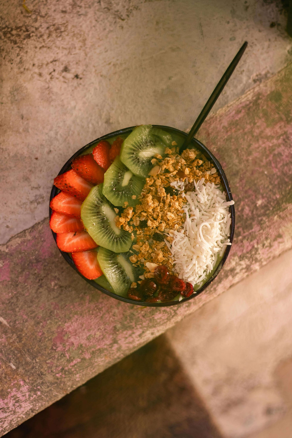 Breakfast bowl with strawberries, kiwi, shredded coconut, and granola.