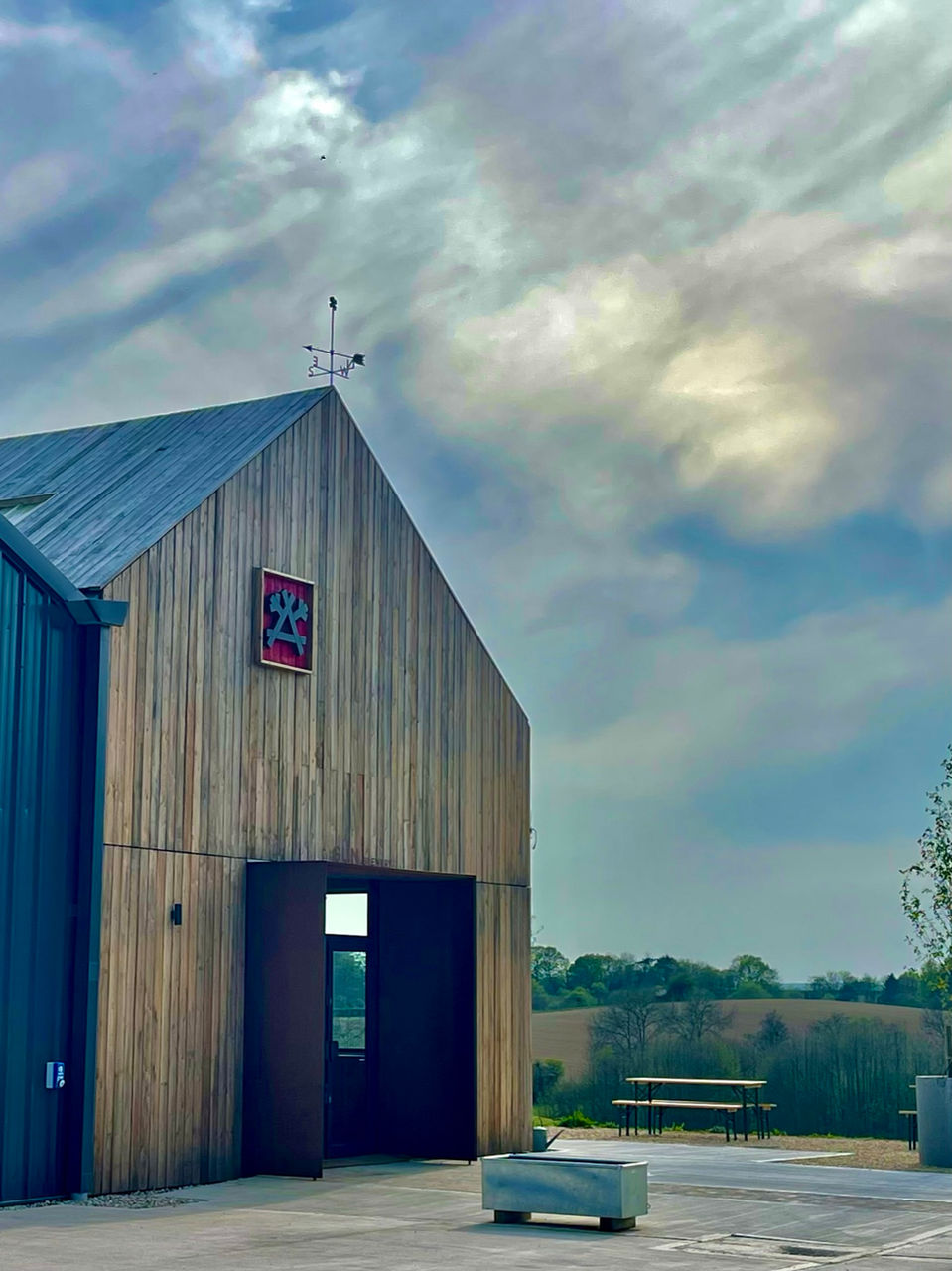 view of gun brewery taproom.  Rustic vertical timber cladding and rusty metal details. cloudy sky
