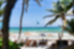 A man parasailing on the ocean in front of the sunbeds of Alaya Tulum, an eco resort in Tulum