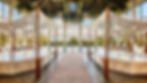 A luxurious indoor spa with marble lounge beds, canopy drapes, and a serene pool surrounded by large windows and greenery, offering a tranquil retreat at an eco-friendly honeymoon resort in Costa Rica.