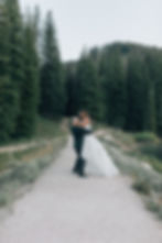 Groom picking up bride with forest background