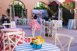 Various striped linened tables with centerpieces and white chairs