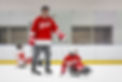 An adult pushing a youth player in a hockey sled