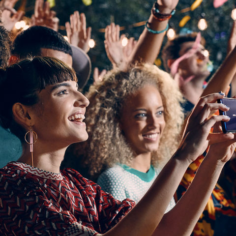 A diverse group of people capturing photos with their smartphones in an outdoor setting.