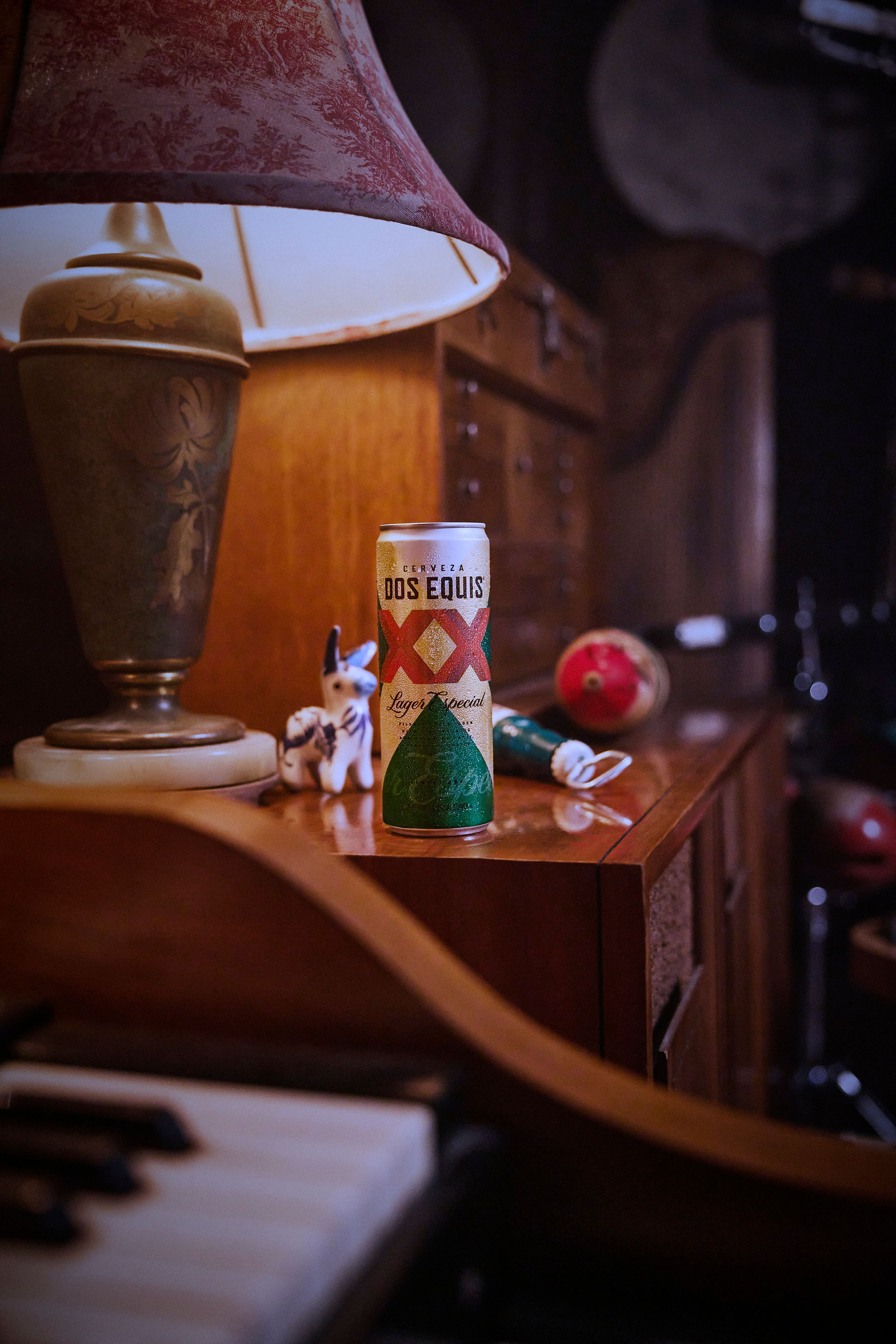 wide angle of a can of DosEquis Over a table besides a lamp