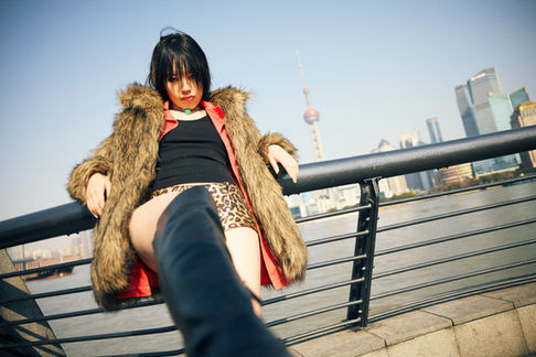 Urban lifestyle photography in Shanghai with skyline view and Fei posing on a riverside railing