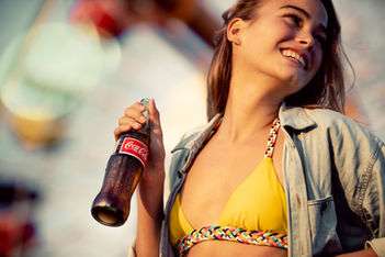 Candid lifestyle photo of woman in bikini top enjoying Coca-Cola outdoors