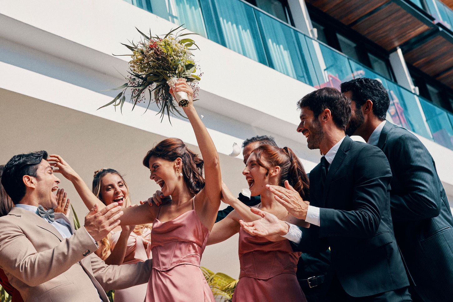 A group of people joyfully tossing a bouquet into the air, celebrating a special occasion together. 