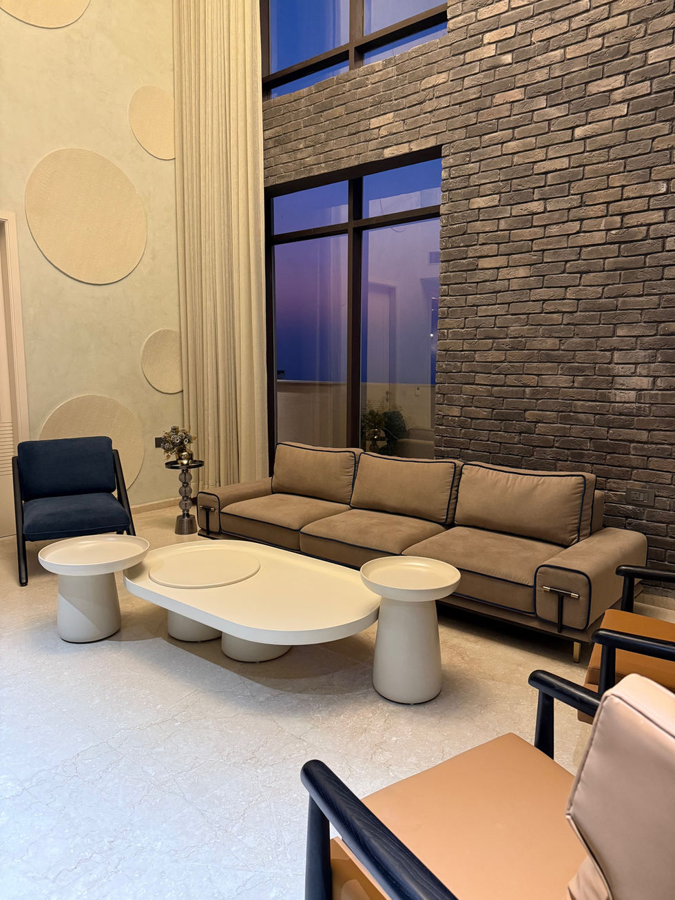 Modern living room with stylish furniture and brick wall.