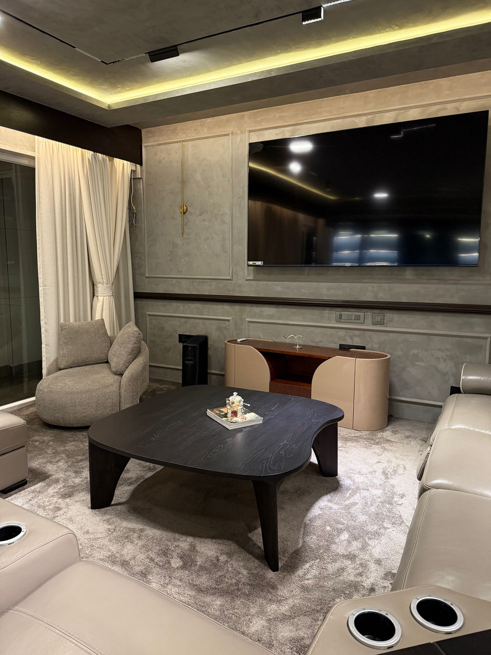 Modern living room with large TV and elegant furniture.