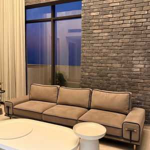 Modern living room with brick wall and beige sofa.