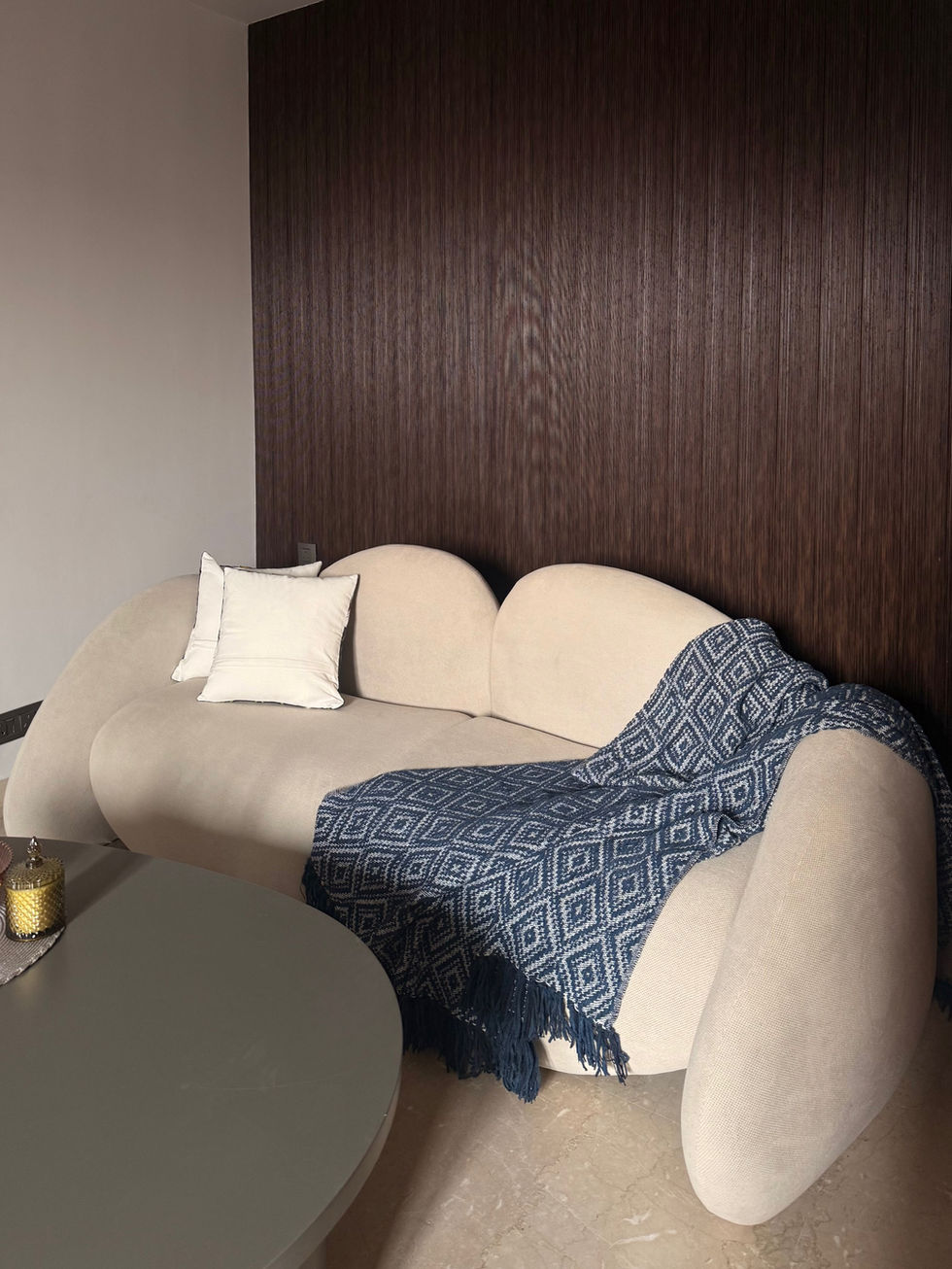 Beige sofa with blue patterned throw blanket.