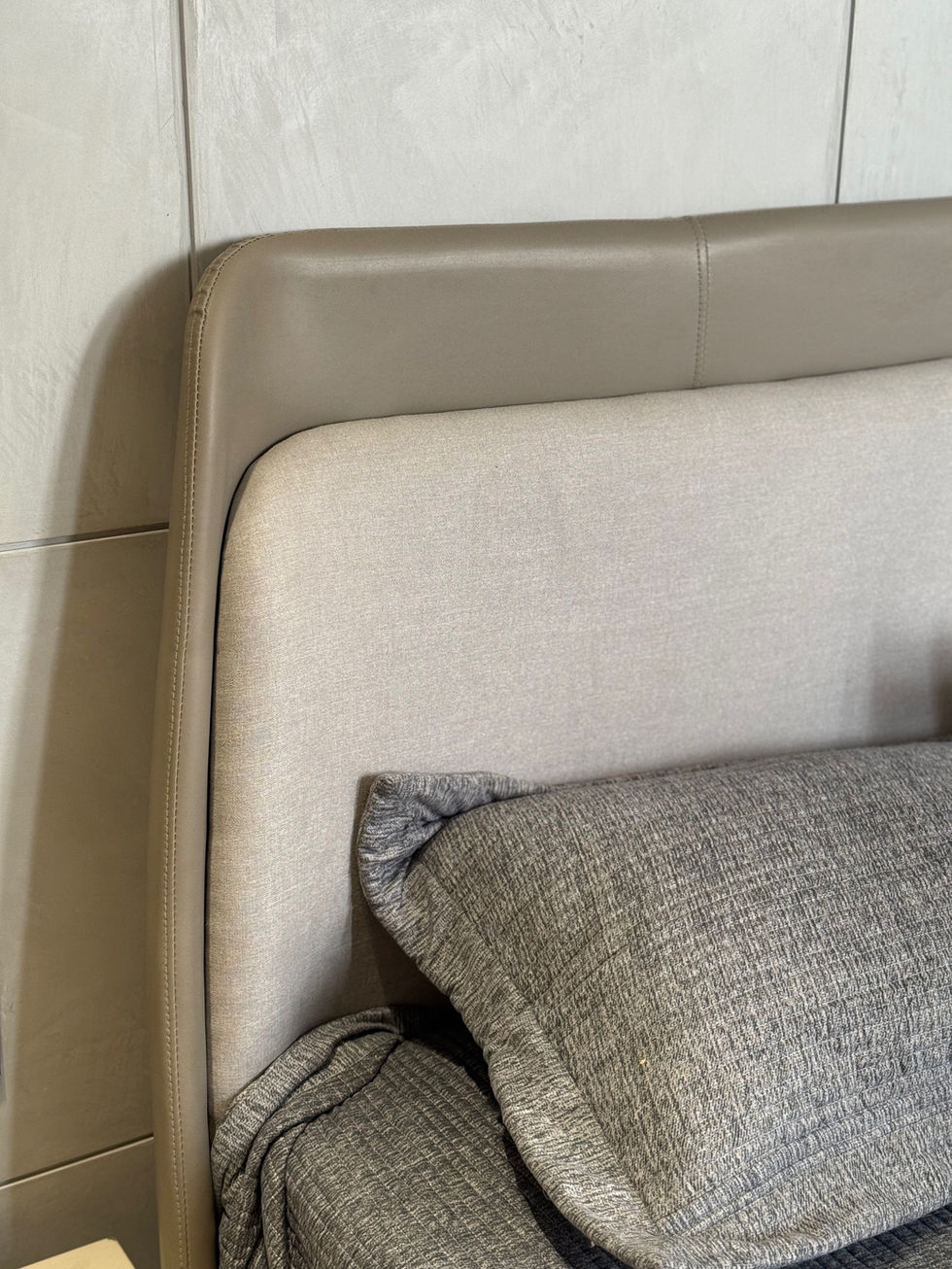 Beige upholstered headboard with gray pillows.
