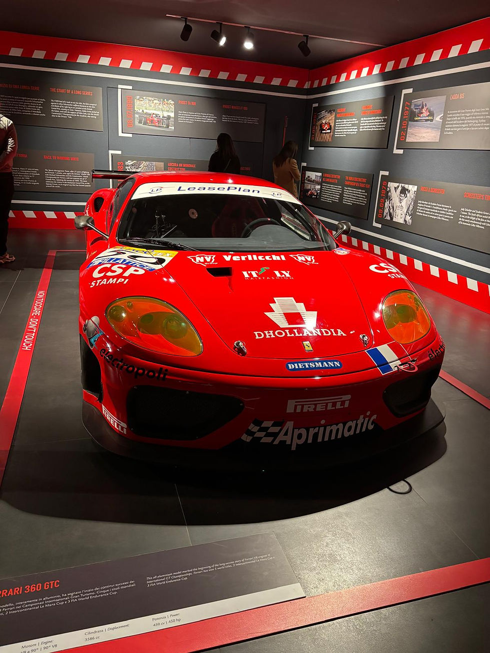 Ferrari 360 GTC racing car on display at the Museo Ferrari in Maranello, Italy, featuring red livery with LeasePlan and Pirelli sponsorship logos