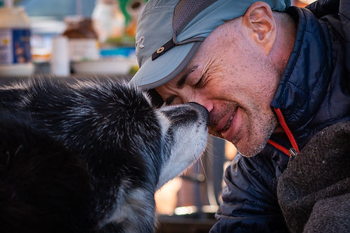 Craig Sheckler being comforted by Miki the malamute at an aid station near the 100 mile mark of the Moab 240 Endurance Run