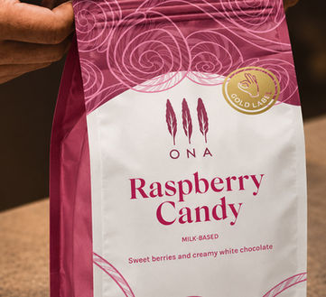 Hands holding an ONA Raspberry Candy coffee bag, packaging photography