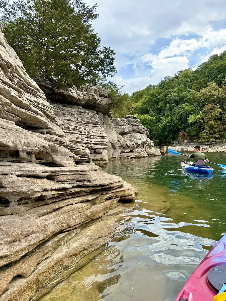 Kayaker paddling past limestone cliffs on Beaver Lake