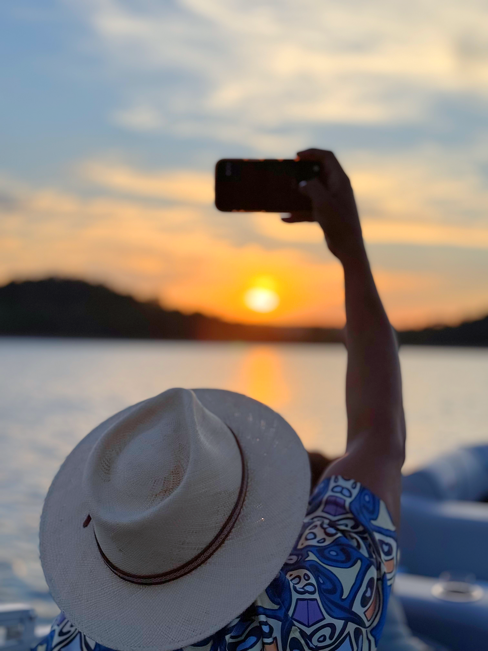 Person photographing a sunset over the water