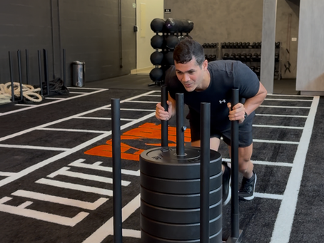 Foto do treino na Elite Core, mostrando o espaço amplo e o movimento (esteira, trenó, remador).