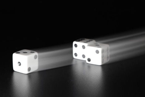 White dice rolling on a black surface, representing noise, uncertainty and risk allocation