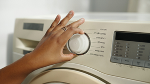Hand adjusting washing machine dial surrounded by options, symbolizing access economy dignity