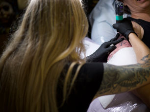 A tattoo artist tattooing a client's upper arm