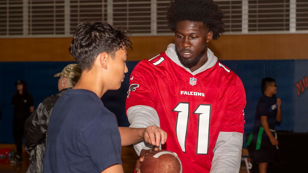 Jalon Walker in his current red number 11 Atlanta Falcons jersey instructing a youth football clinic participant in June 2026.